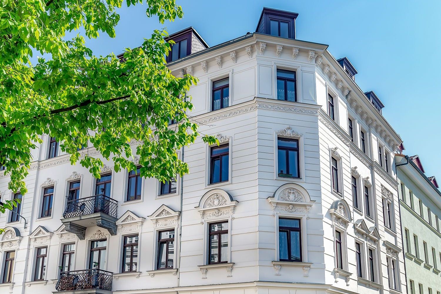 Fassade von einem hellen Wohngebäude mit Verzierungen über dem Fenster