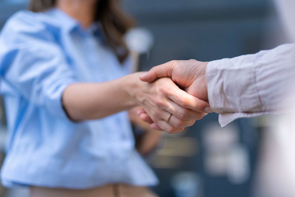 Zwei geschäftlich gekleidete Personen reichen sich die Hand