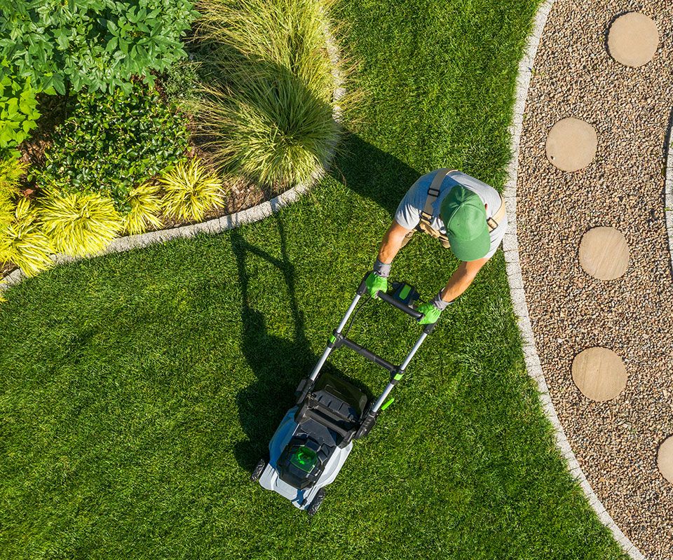 Ein Arbeiter mäht den Rasen in einem gepflegten Garten
